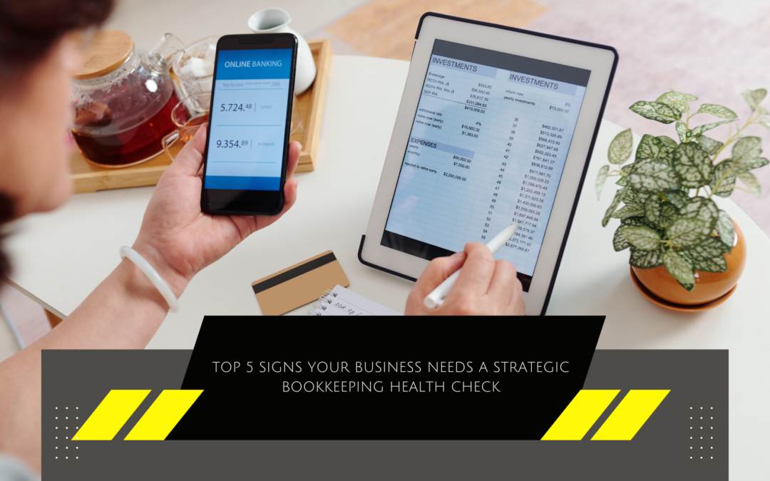 A person checks financial data on a smartphone and a tablet, with a calculator, notepad, and credit card nearby. The image includes text 'TOP 5 SIGNS YOUR BUSINESS NEEDS A STRATEGIC BOOKKEEPING HEALTH CHECK